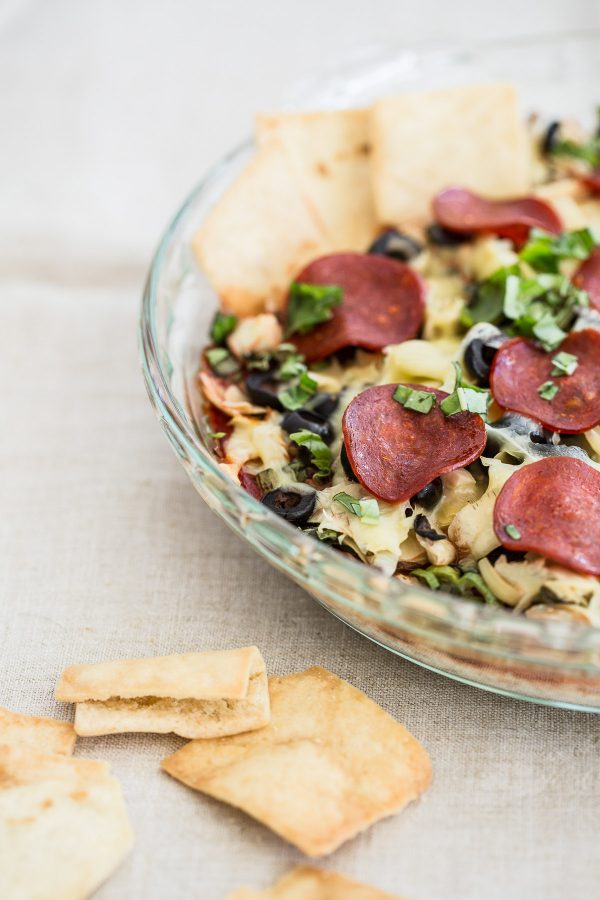 Layered Pepperoni Pizza Dip Recipe - a cheesy dip with artichokes, black olives, cream cheese, mozzarella, and basil that tastes just like a pepperoni pizza! The most delicious light appetizer!