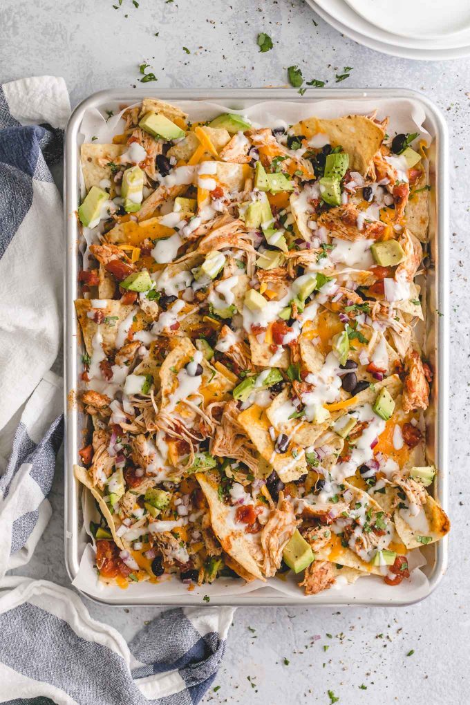 The Best Lighter Chicken Nachos! 396 calories or 8 WW points. Piled high with crisp tortilla chips, delicious and easy slow cooker Mexican shredded chicken, seasoned black beans, melted cheddar cheese, and all the fixins!