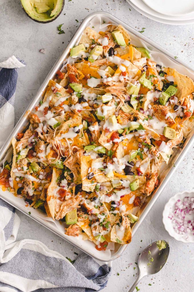 The Best Lighter Chicken Nachos! 396 calories or 8 WW points. Piled high with crisp tortilla chips, delicious and easy slow cooker Mexican shredded chicken, seasoned black beans, melted cheddar cheese, and all the fixins!